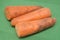 Poorly washed carrots lie on a green background, carrots deteriorate, proper nutrition.