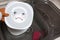 Poorly washed dishes in kitchen sink. Female hand holding white plate with eyes, sad emotion