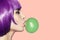 Pop art woman blowing bubble gum. Side view on pink background.