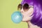 Pop art woman portrait wearing purple wig. Blow a blue bubble