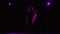 A pop vocalist performs on a dark stage illuminated by purple light. A dark silhouette of a woman with long beautiful