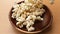 Popcorn fall into a wooden plate on a table