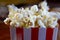 Popcorn flying out of cardboard box. red and white striped popcorn bucket with flying popcorn in the living room, movie