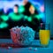 Popcorn in a glass plate with a drink on the background of the TV. Color bright lighting. Background