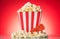 Popcorn in large square box and around, movie ticket on bright r