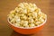 Popcorn in orange bowl. Brown background
