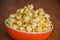 Popcorn in orange bowl Brown background