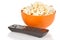 Popcorn in a orange bowl and remote control