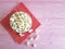 Popcorn plate natural , red napkin in a polka dot pink wooden background with space for text