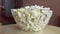 Popcorn in a plate on a wooden round tray, in motion