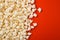 Popcorn scattered on a red background. A classic movie theater snack. View from above