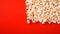 Popcorn scattered on a red background. A classic movie theater snack. View from above