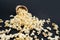 Popcorn spills out of a brown paper cup on a black background close-up