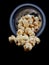 Popcorn spills out of a plastic glass. Isolate on a black background