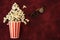 Popcorn in a striped paper Cup and popcorn flies out with movie glasses on a red background with space for text. Flat Lay, Top Vie