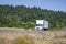 Popular day cab middle duty rig semi truck with box trailer making local delivery running on the scenic road with meadow and