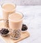 Popular Taiwan drink - Bubble milk tea with tapioca pearl ball in drinking glass on marble white table wooden tray background,