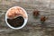 A porcelain bowl filled with large crystals of pink himalayan salt and black peppercorns on an old weathered board, with star