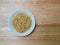 Porcelain bowl filled with pine nuts on chopping block, overhead