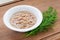 Porcelain bowl with shredded tuna in oil for cooking salad and green dill on a wooden background. Seafood, healthy eating and cook