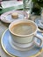 Porcelain Coffee Cup with Macaroon / Macaron at Cafe Shop with Cream served on Marble table