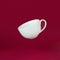 Porcelain cup flying with marshmallows on a red background. Gravity , levitation concept