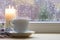 Porcelain cup of tea and a candle by the window