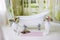 Porcelain freestanding bath in designed white bathroom. White luxurious bath, a bouquet of flowers in a large vase. Still life or