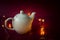 Porcelain kettle and Christmas lights on a burgundy background