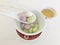 A porcelain spoon scoops three glutinous rice balls of taro, red beans and sesame flavors with tea on white marble background.