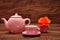 A porcelain spotted tea cup and kettle and an orange rose