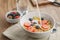 Poring milk into corn flakes with berries in bowl on table