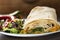 Pork and beef fajita wrap sandwich with salad on plate