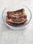 Pork belly slices marinated in soy sauce and herbs in a glass bowl on a light table cloth