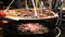 Pork, chiken and beef grilled sausages are fried in a large pan over an open fire. S
