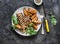 Pork chop with caramelized grilled apples and arugula salad on a dark background, top view