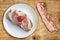 Pork Gammon Ham And Cheese Sandwich With Cherry Tomato On Porcelain Plate And Bacon Rasher Alongside Set On Old Picnic Table