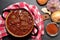 Pork goulash in the old enameled saucepan on a checkered red tablecloth. Onion, garlic and pepper spice. View from top.