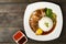 Pork leg rice with boiled egg in gravy and kale in white dish on wooden table