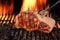 Pork Loin Steak On Hot Flaming Barbecue Grill With Fork