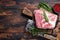 Pork neck raw meat for fresh Chop steaks on wooden cutting board with butcher cleaver. Dark wooden background. Top view