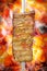 Pork rib, traditional brazilian barbecue whole piece on skewer isolated on blurred ember background.