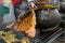 Pork ribs grilled next to a large ceramic pot. Street food of Ecuador