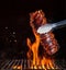 Pork ribs over flaming grill grid, on black background.