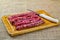 Pork sausage. thin pork sausage on wooden cutting board with knife next to it on jute fabric
