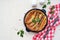 Pork sausages baked in pastry for Yorkshire pudding in a serving cast-iron skillet on a light concrete background. Toad in a hole