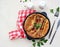 Pork sausages baked in pastry for Yorkshire pudding in a serving cast-iron skillet on a light concrete background. Toad in a hole