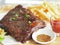 Pork Spareribs BBQ, Barbeque Pork Ribs with french fries vegetable salad, tomato sauce in a clear glass on wooden tray, food