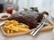 Pork Spareribs BBQ, Barbeque Pork Ribs with french fries vegetable salad, tomato sauce in a clear glass on wooden tray, food