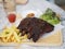 Pork Spareribs BBQ, Barbeque Pork Ribs with french fries vegetable salad, tomato sauce in a clear glass on wooden tray, food